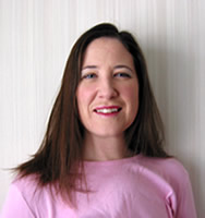 A closeup of Jane Davis, who is wearing a pink sweater with her hair down and red lipstick, in front of a white background